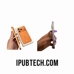 Perbandingan dua ponsel pintar dari sisi samping: di kiri, tangan memegang ponsel oranye tembaga di samping kotaknya; di kanan, tangan lain memegang ponsel perak/putih yang terlihat dari sisi tombol